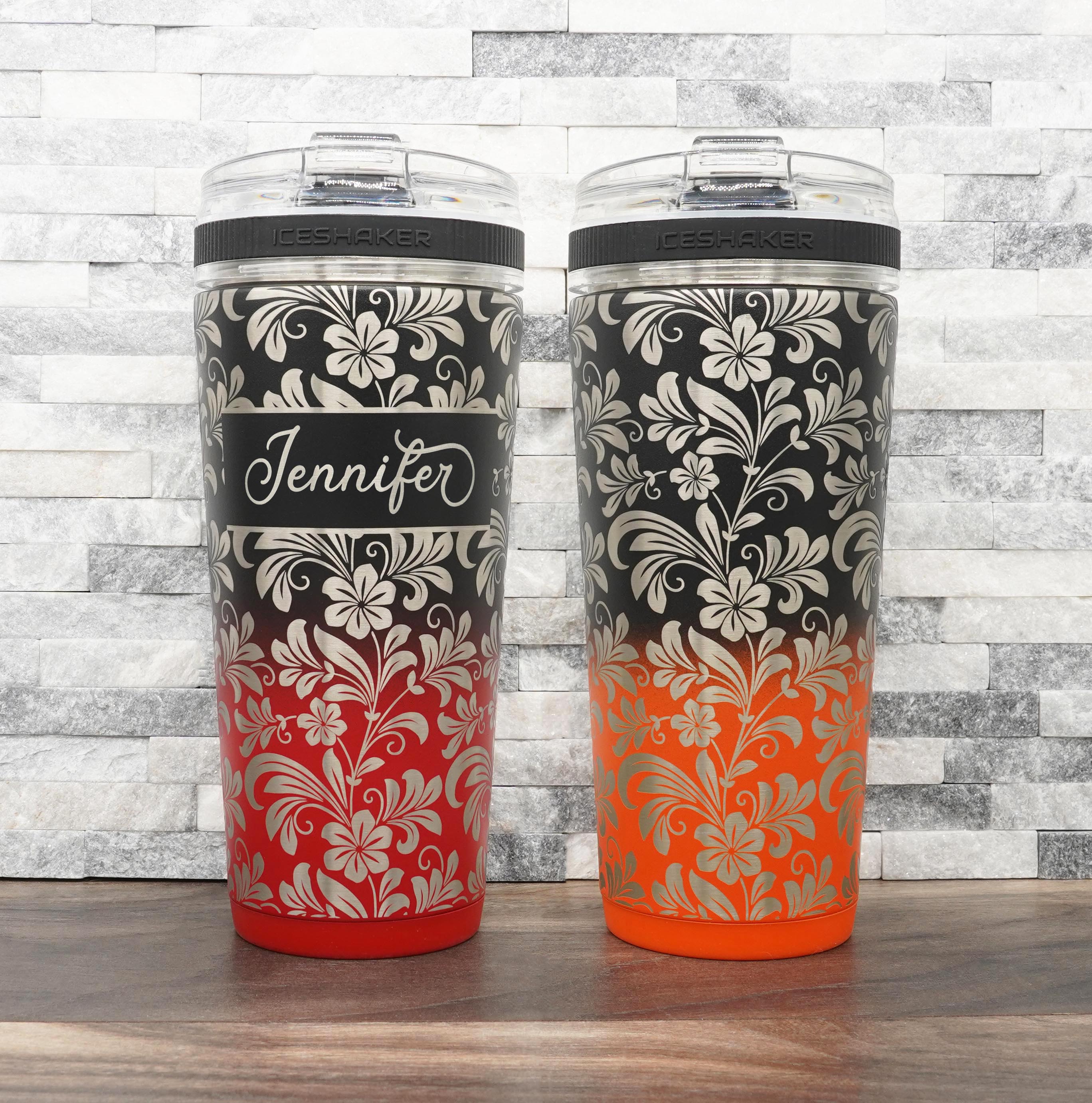 Ice Shaker Flex Bottle laser engraved with hibiscus flower pattern, shown both personalized and with just the design, in the black/red two-tone finish and black/orange two-tone finish.